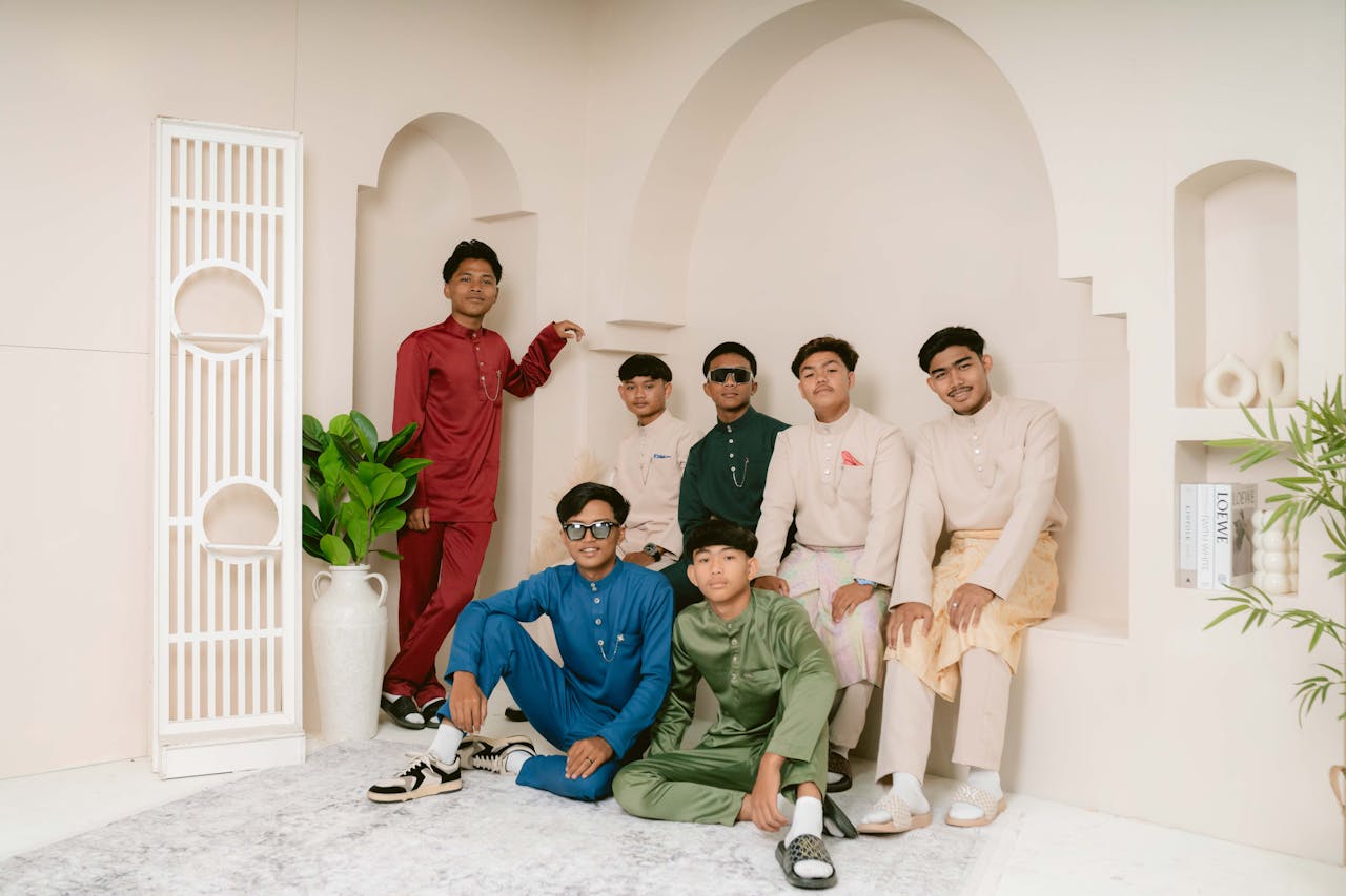 Young men posing in culturally rich traditional attire indoors with decorative elements.